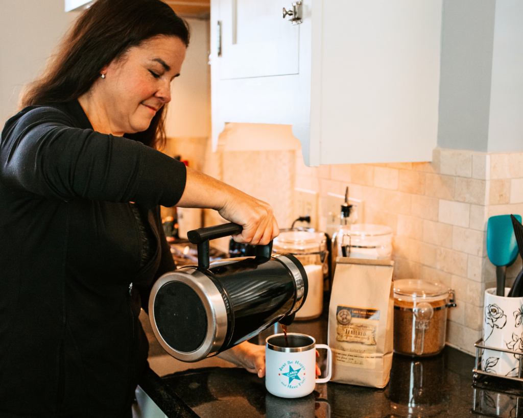 Coffee bundle of coffee, mug, and French press. Lady pours coffee from her French press into her new Cabin Coffee mug.